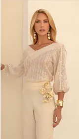 Blusa color blanco hueso de tejido calado con lentejuelas, escote en V y mangas 3/4 abullonadas.