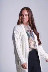 Saco tejido color crema con diseño de ochos y bolsillos frontales.