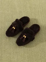 Mocasín marrón de cuero vacuno y gamulán de oveja, con borlas en el empeine y terminales doradas. Suela de goma.