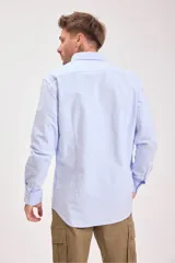 Camisa celeste de manga larga con cuello clásico y cierre abotonado.