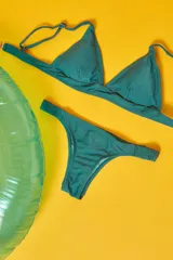 Conjunto de bikini blanco con textura, compuesto por un corpiño de triángulo fijo con breteles regulables y almohadillas desmontables, y una bombacha vedetina con frunce elástico en los costados.