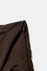 Falda pantalón negra de tiro bajo con cintura drapeada y bajo acabado en volantes superpuestos. Presenta un lazo largo y fino que cae desde el lateral.