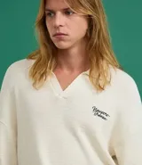 Camisa polo de hombre confeccionada en tejido de punto de algodón, color crema, con cuello en V y manga corta. Presenta un corte oversized y un pequeño bordado de lettering en el pecho.