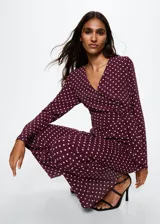 Mono largo color borgoña con estampado de lunares blancos, escote en V cruzado, mangas largas acampanadas, nudo en la cintura y forro interior.