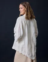Camisa color crudo con bordado tipo broderie, cuello con solapa, manga tres cuartos y cierre frontal con botones.