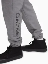 Pantalón de jogging gris de algodón, con cintura elástica, bolsillos laterales y traseros, y logo de Calvin Klein bordado en la pierna izquierda.