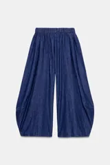 Pantalón de denim azul con cintura elástica ajustable con cordones interiores y pierna ancha con volumen.