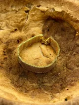Pulsera dorada de malla metálica flexible con cierre de mosquetón.