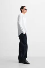 Camisa blanca de algodón, corte slim fit, cuello italiano, manga larga con puños abotonados y cierre frontal con botones.