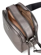 Cartera bandolera de cuero sintético color blanco con logo dorado en el frente. Tiene correa ancha de tela estampada con motivos geométricos y herrajes dorados. Incluye un dije de flecos de cuero en el lateral.