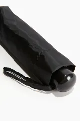 Paraguas negro plegable con funda y mango telescópico.
