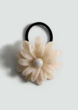 Accesorio para el pelo con forma de flor color crema y centro grisáceo, sujetado a una banda elástica negra.
