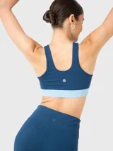 Top deportivo azul con detalle de abertura en la parte frontal sobre el busto y almohadillas removibles.