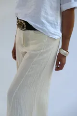 Pantalón de lino color crudo, de corte palazzo, con bolsillos laterales y cintura alta.