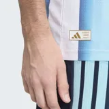 Camiseta de fútbol Adidas de la Selección Argentina, modelo titular 2026, versión jugador. Diseño a rayas verticales celestes y blancas, con cuello redondo y detalles en azul marino en las mangas y hombros. Incluye escudo de la AFA y logo de Adidas en dorado, además del parche de campeón FIFA.