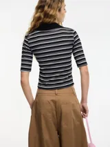 Top ajustado al cuerpo con cuello tipo polo, a rayas horizontales blancas y negras, con botones en el escote y mangas cortas.