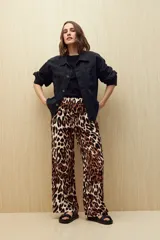 Pantalón ancho de tela liviana con estampado de hojas color crema sobre fondo azul. Tiene cintura elastizada con lazo ajustable.