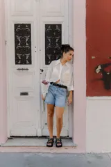 Cinturón de cuero negro liso con hebilla metálica redonda de color plateado.