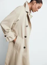 Abrigo largo estilo trench coat color beige, con doble botonadura, cuello de solapa ancha, manga larga con puños abotonados y cinturón desmontable. Presenta un diseño recto y oversize.