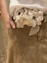 Cinturón de flores artesanales confeccionadas en una mezcla de tejidos, combinando texturas en tonos crudos.