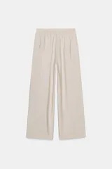 Pantalón ancho color beige de tiro alto con cintura elástica y bolsillos delanteros.