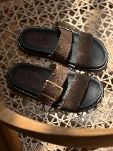 Sandalias marrones de cuero con doble tira y hebilla metálica, suela de goma.