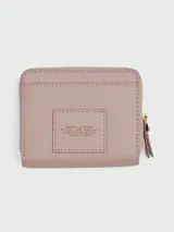 Billetera compacta Marc Jacobs de cuero color lila con cierre de cremallera y logo estampado en el frente.