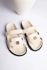 Sandalia plana color beige con dos tiras anchas en el empeine y suela negra.