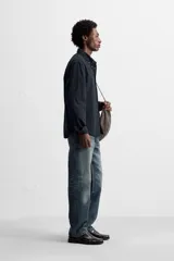 Camisa azul de algodón con textura chambray, corte regular fit, cuello abotonado, manga larga con puños abotonados, bolsillo de parche en el pecho y cierre frontal con botones.