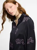 Camisa de seda verde con estampado de tigres en blanco, corte holgado y botones frontales.