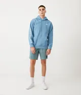 Bermuda masculina de sarga color verde azulado con efecto jaspeado, cintura elástica con cordón de ajuste, bolsillos laterales y traseros, y etiqueta en la parte inferior.