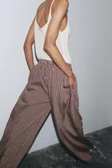 Pantalón de tiro medio con cintura elástica y bolsillos laterales ocultos en costura. Pierna ancha y estampado a rayas verticales color borgoña y blanco.
