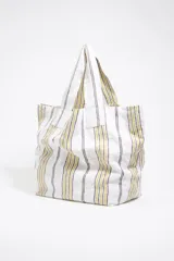 Bolso tipo shopper de lona color crudo con rayas verticales amarillas y grises. Tiene doble asa de hombro y logo de la marca estampado en el frente.
