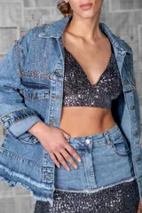 Campera de jean celeste con apliques de strass y cadenas en hombros y bolsillos.