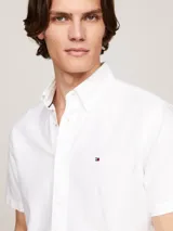 Camisa blanca de algodón Oxford, de corte regular, con cuello abotonado, manga corta y logo de Tommy Hilfiger bordado en el pecho.