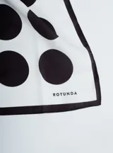 Pañuelo cuadrado de seda color blanco con estampado de lunares negros y borde negro.
