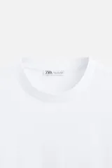 Camiseta blanca de algodón compacto, corte relaxed fit, cuello redondo y mangas cortas.