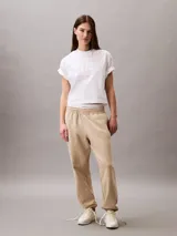 Pantalón de jogging color beige de felpa de mezcla de algodón, con cintura elástica ajustable con cordón, bolsillos laterales, bajos de canalé y logo CK bordado en la pierna.