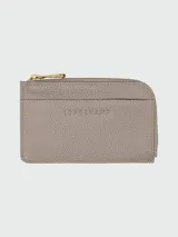 Tarjetero Longchamp de cuero color gris con cierre dorado y logo grabado.