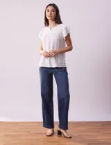 Blusa blanca labrada con cuello a la base, escote en V y aplique metálico. Tiene mangas cortas superpuestas.