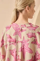 Vestido camisero corto de lino color blanco con estampado de estrellas de mar y algas en azul. Tiene cuello mao, mangas largas y cierre frontal con botones.