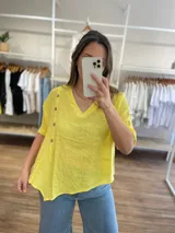 Blusa celeste de lino con cuello en V, mangas cortas con dobladillo y cierre lateral con botones de madera.
