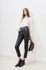 Pantalón negro de cuero ovino con cintura alta y corte cigarette.