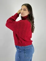 Polerón de punto color crema con cuello alto y diseño de trenzas.