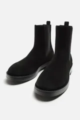 Bota Chelsea de cuero negro con elástico lateral, tirador trasero y suela con ligero tacón.