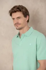 Chomba azul marino de piqué con cuello clásico, tapeta de dos botones y logo de pájaro bordado en color rosa en el pecho.