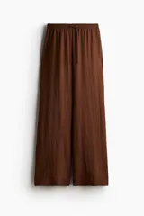 Pantalón marrón de punto, corte holgado, tiro alto, cintura elástica con cordón ajustable y perneras anchas.