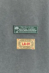 Camiseta gris de algodón con efecto lavado, cuello redondo, manga corta y parches estampados en el frente.