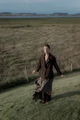 Pollera larga de poliéster color gris, con diseño plisado y caída fluida.