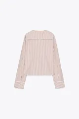 Camisa de popelina a rayas marrones y blancas, con cuello bobo con puntilla y escote pico con lazada. Manga larga con puño y cierre frontal con botones.
